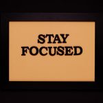Minimalist black frame with 'Stay Focused' text on beige background.